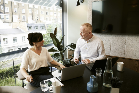 A man and woman sit at a desk discussing a secondment